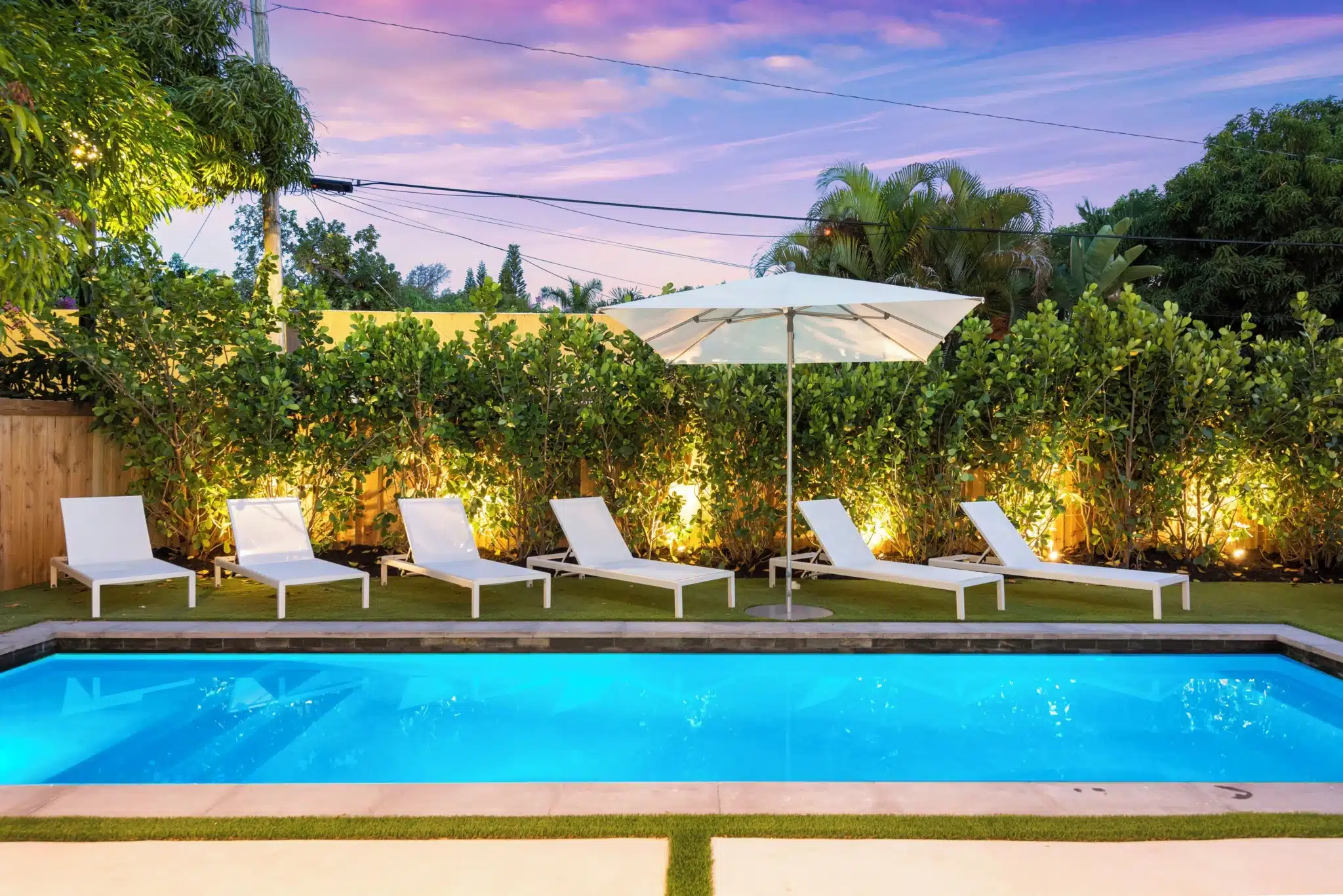 Luxury backyard pool with lounge chairs and tropical landscaping in Miami Beach