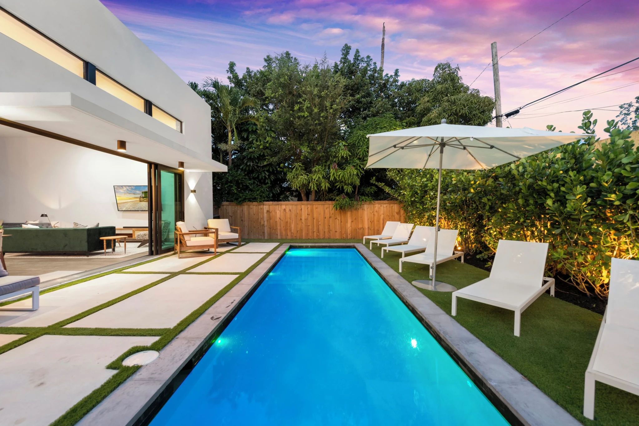 Vacation home rental Miami backyard with turquoise lap pool and lounge chairs at dusk