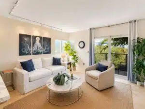 Modern living room with cream sectional, navy pillows, marble coffee table and balcony view in a Miami short term rental by