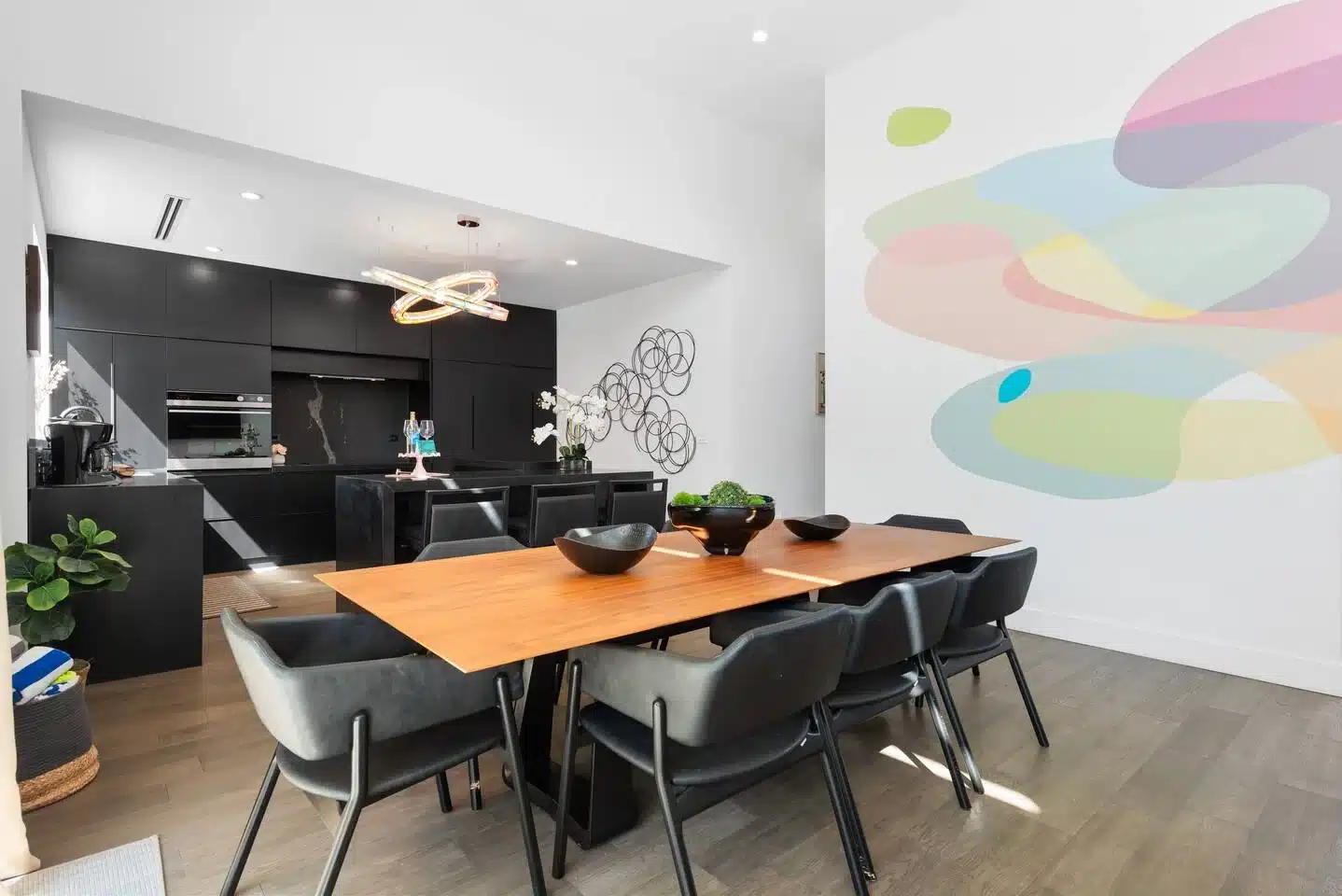 Modern open-concept dining and kitchen with colorful abstract wall art in Miami vacation rental