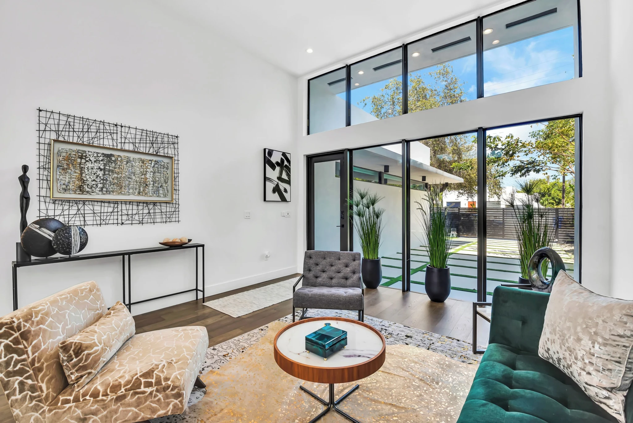 Bright living room with sliding glass doors to patio, beige patterned sofa, green accent chair, black console table, in a