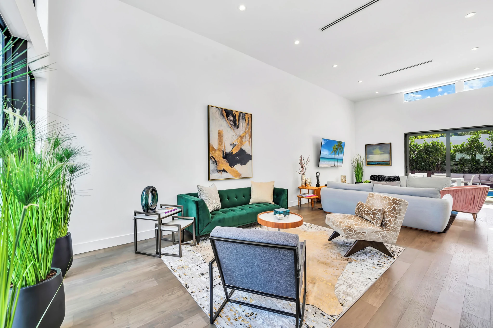 Bright living room with green velvet sofa, blue chairs, and plants at a Wynwood murals near Miami short term rental in the