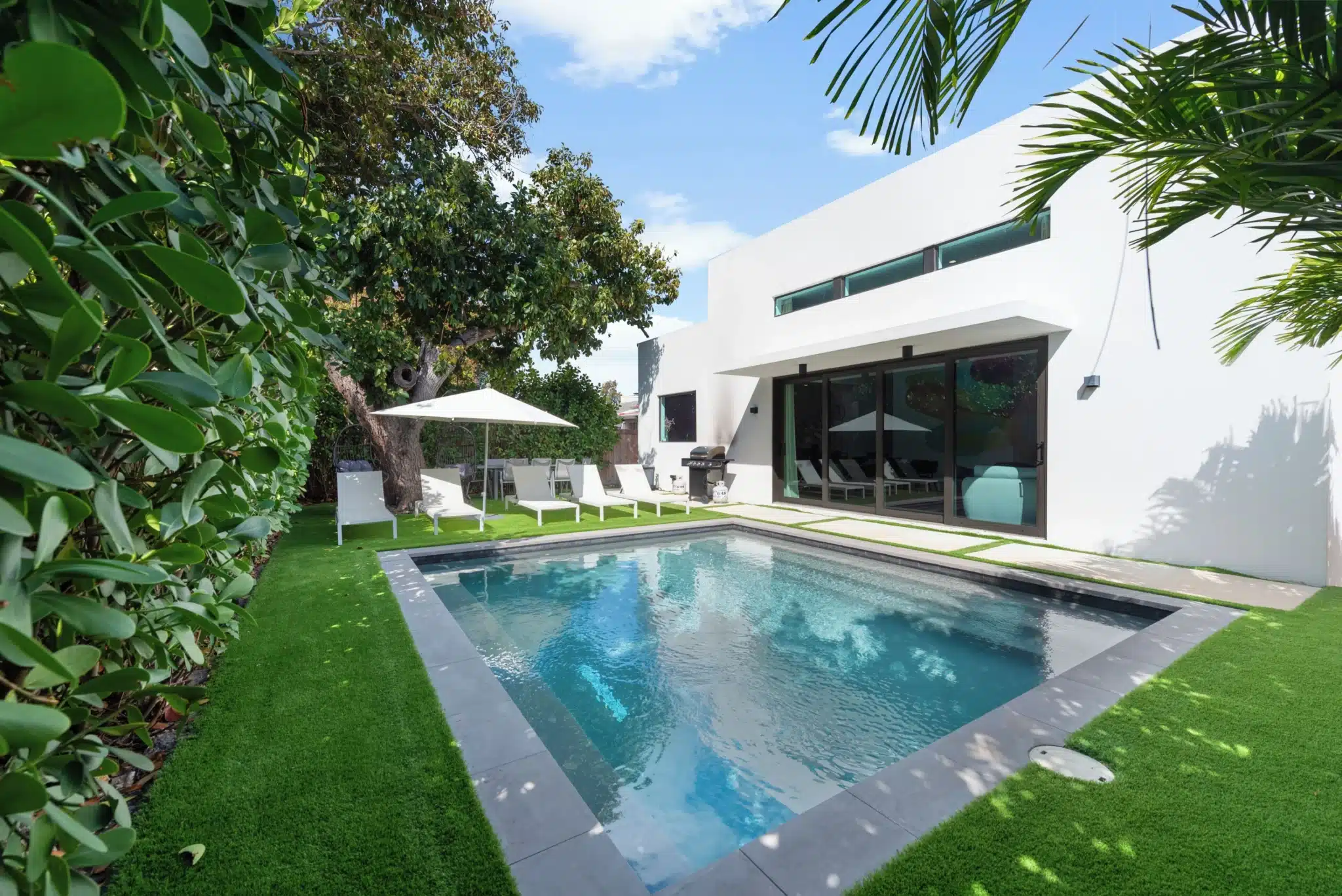 Modern backyard pool with white loungers for downtime in a Miami itinerary