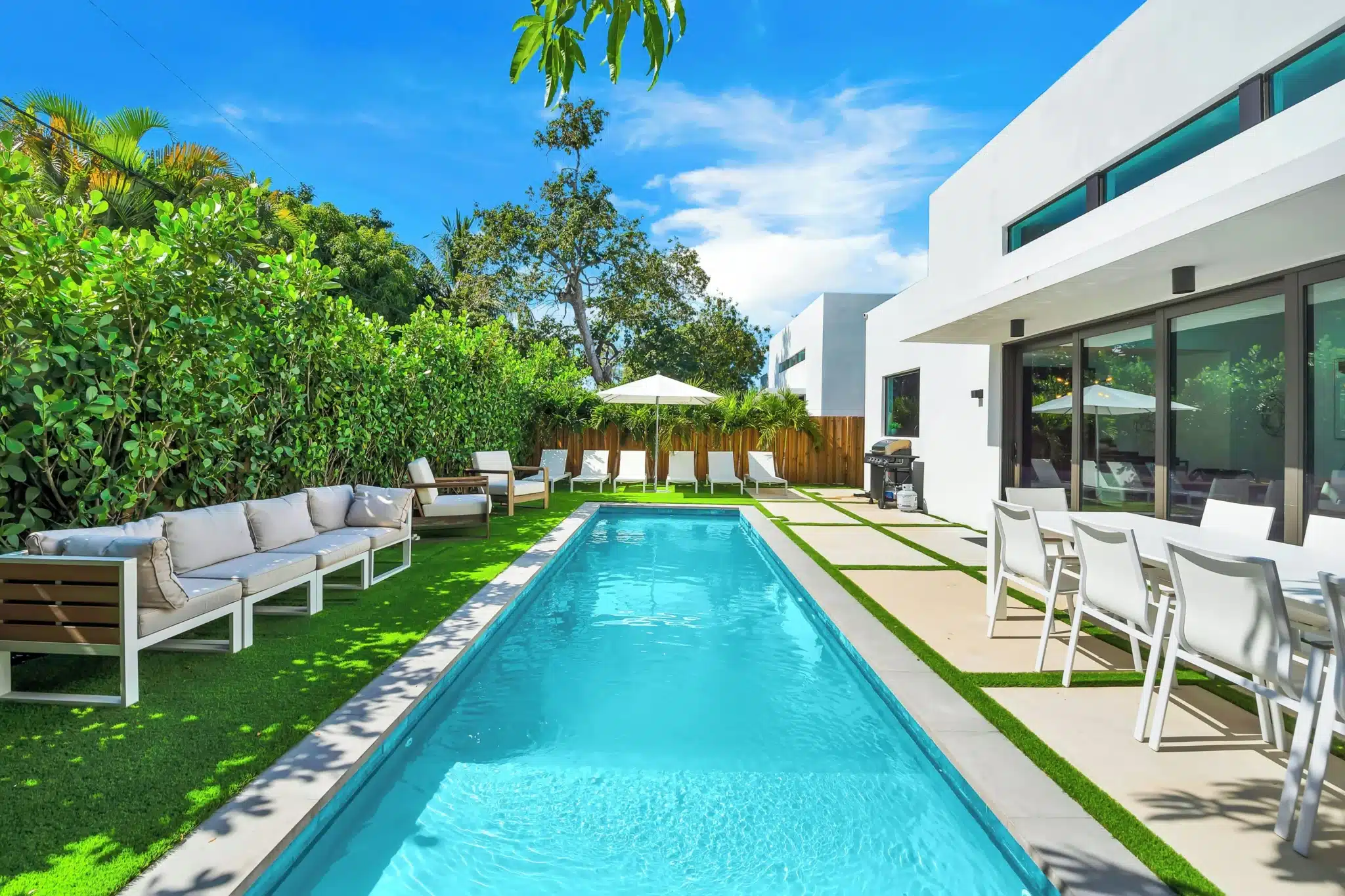 Modern backyard pool with lounge chairs for relaxing pool days at Miami residential property