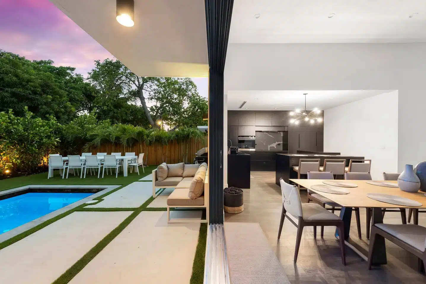 Modern open-plan living with kitchen, patio, and pool at twilight in Miami Beach